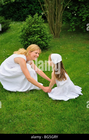 Young mother and daughter playing in meadow Stock Photo