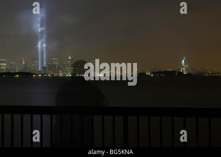 Ghosted person looking out on the 9/11 memorial tribute lights with the Brooklyn Bridge and Statue of Liberty in the background. Stock Photo