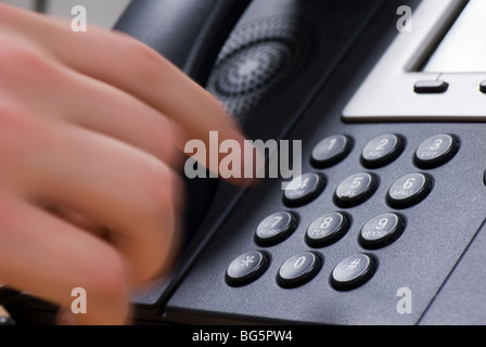 Hand dialing a phone number on a modern keypad. Stock Photo