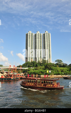 Golden barge taking visitors from Aberdeen Promenade to the Jumbo Floating Restaurant, past three tower blocks, Hong Kong, China Stock Photo