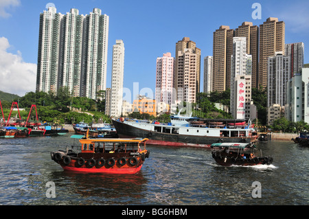 Two sampans passing each other, against a backdrop of fishing boats and tower blocks, Aberdeen Harbour, Hong Kong, China Stock Photo