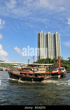 Portrait shot of a large fishing boat moving eastwards, past three high rise buildings, Aberdeen Harbour, Hong Kong, China Stock Photo