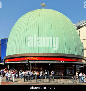 People in London street scene below green patina coating on copper roof of dome at part of Madame Tussauds Wax Museum complex London England UK Stock Photo