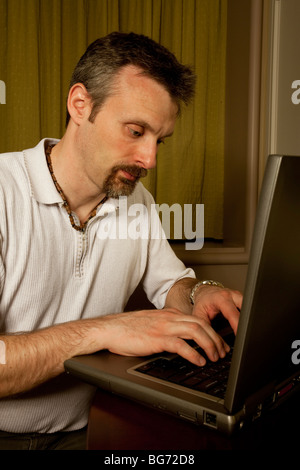 close up of man typing on a laptop in a hotel room Stock Photo