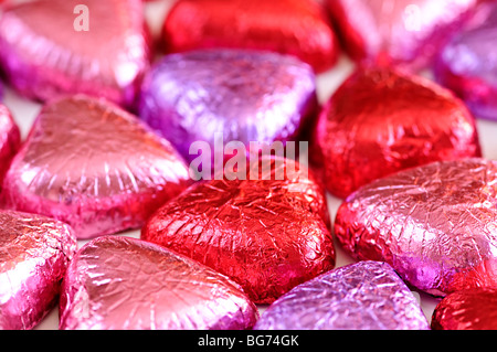 Background of Valentine's chocolates wrapped in red and purple foil Stock Photo