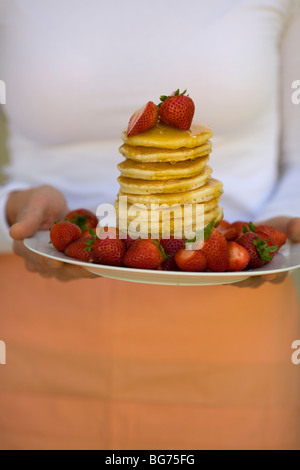 crop of flapjacks, strawberries and syrup being served on plate Stock Photo