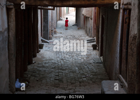 A little girl in an old alley in the Old Town of Kashgar, Xinjiang province, China Stock Photo