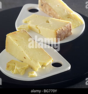Cheddar cheese wedges on white flat plates Stock Photo