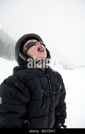 a young boy catching snowflakes on tongue Stock Photo