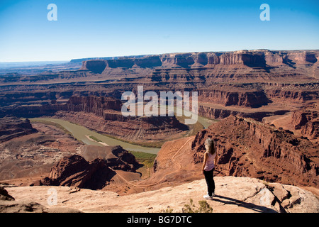 A active older woman looks out over the Colorado River from Dead Horse Park, adjacent to Canyonlands National Park in Moab, Utah Stock Photo
