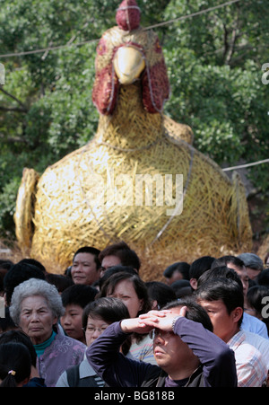 People watch performance in front of golden chicken during Chinese New Year. Stock Photo