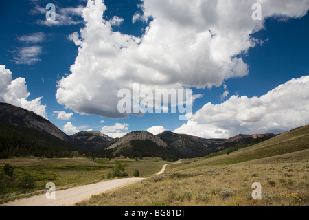 A long dirt road winds near the the foothills of the Rockies in Montana. Stock Photo