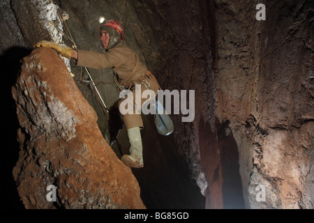 A cave explorer makes his way through a cave called 'Asopladeru la Texa' 1000m deep underground in The Picos de Europa, Spain. Stock Photo