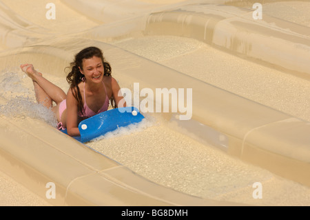 Young laughing woman on a water slide in a waterpark. The image has a slight motion blur. Stock Photo