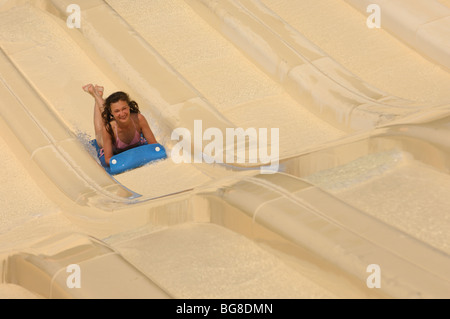 Young laughing woman on a water slide in a waterpark. The image has a slight motion blur. Stock Photo