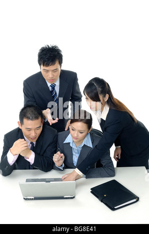 Two businessmen and two businesswomen working on a laptop Stock Photo