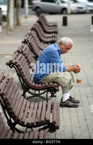OLD MAN, SIESTA, BARCELONA, THINKING: An old man sitting alone on a bench during siesta in a city park Barcelona Catalonia Spain Stock Photo