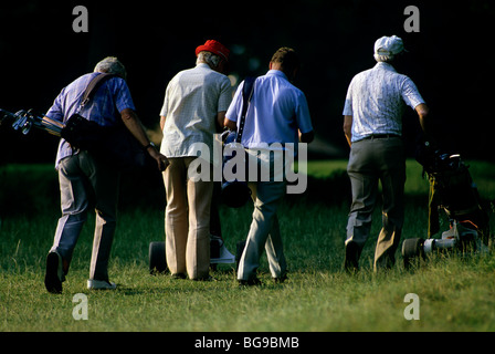 Golfers wheeling and carrying their golf bags across a golf course Stock Photo