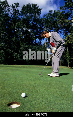 Golfer watches the ball approach the golf hole Stock Photo
