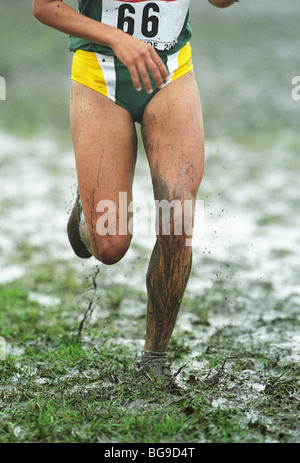 Long distance runner running through muddy grass Stock Photo
