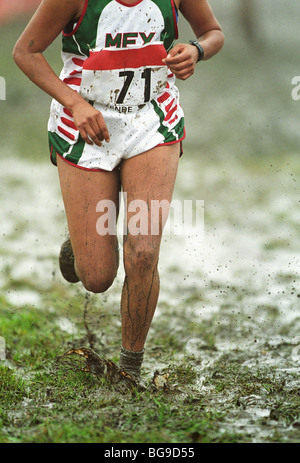 Long distance runner running through muddy grass Stock Photo