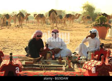 Three Qatari citizens relax at a bedouin-style camp on cleared land in the centre of the Qatari capital, Doha. Stock Photo