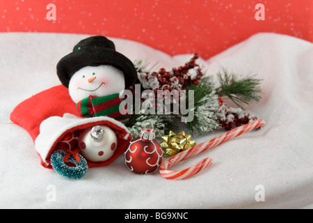 red and white baubles spilling out of christmas stocking with snowman, wreath, bow, and candy cane Stock Photo