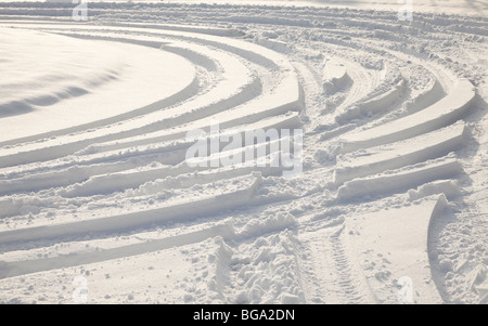 Car tyre tracks in deep snow, winter sun Stock Photo