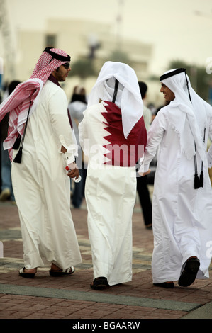 A Qatari national accompanied by two friends wraps himself in Qatar's flag during National Day celebrations on Doha Corniche, Stock Photo