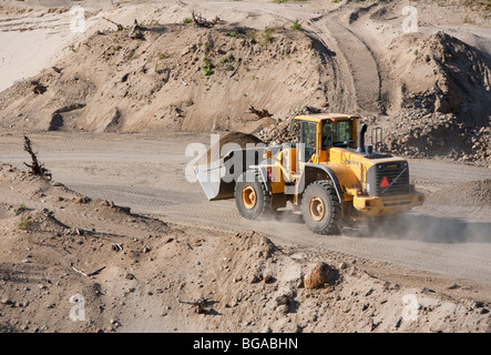 Volvo front loader moving sand in a sandpit at sand quarrying area , Finland Stock Photo