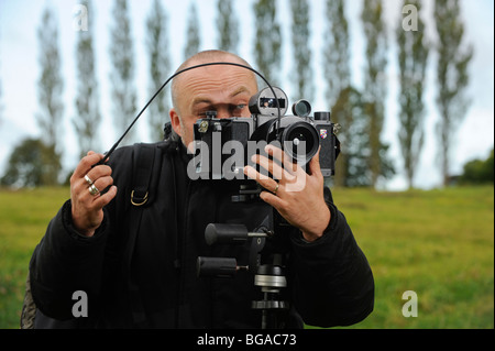 Landscape photographer Tony Wainwright with a 6x17 panoramic camera on tripod working in East Sussex fields. Stock Photo