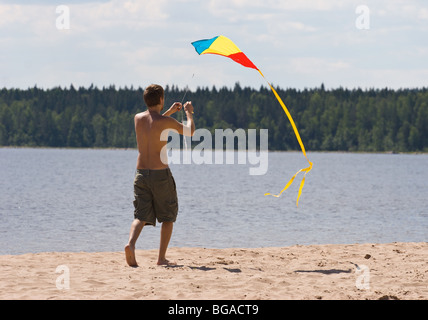 young man flying kite on a lake beach Stock Photo