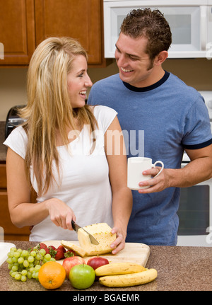 Playful young couple preparing food in their kitchen. Stock Photo