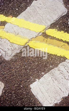 Detail from above of double yellow lines running across white Give Way lines all thickly repainted over old blurred lines Stock Photo