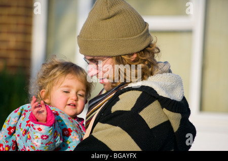 Father Carrying Baby Daughter Wrapped Up In The Cold Stock Photo