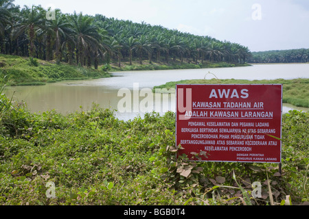 A lake full of rainwater is used for irrigation on the plantation and in the oil mill. Warning sign against trespassing Stock Photo