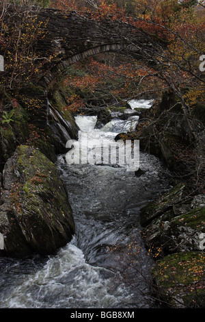 The turbulent Afon Llugwy flows under the bridge of Pont Cyfyng at Capel Curig, Snowdonia, North Wales Stock Photo