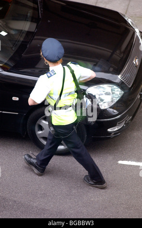 Royalty free photograph showing female traffic warden checking parking ticket in London UK Stock Photo