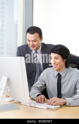 Man in business suit shows young employee something on a computer. Stock Photo