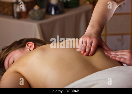 Woman lying down enjoying a relaxing back massage by a masseuse. Stock Photo