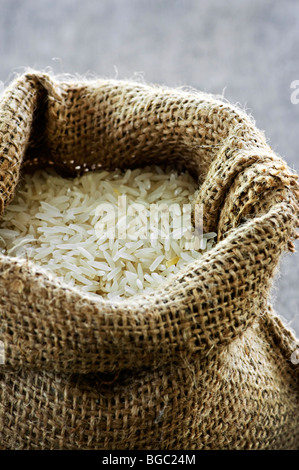 Raw long grain white rice grains in burlap bag Stock Photo