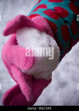 Young girl holds a small snowball in her pink glove Stock Photo