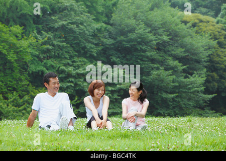 Three people sitting on grass Stock Photo