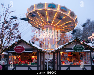 Funfair and small wooden craft shops at dusk at Christmas market in Liseberg amusement park in Gothenburg Sweden Stock Photo