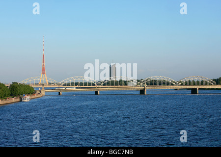 Railway bridge across the Daugava River with radio and TV tower in the background in Riga, Latvia Stock Photo