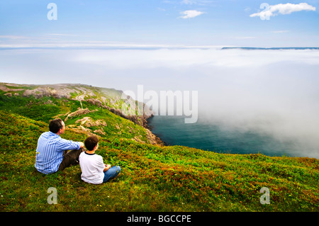 Father and son looking at foggy ocean view in Newfoundland Stock Photo