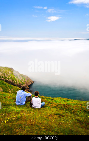 Father and son looking at foggy ocean view in Newfoundland Stock Photo