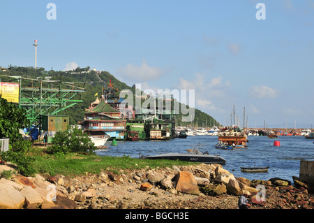 Houseboat, washing line and small boats tied to stern, moored near the Jumbo Restaurant, Aberdeen Typhoon Shelter, Hong Kong Stock Photo