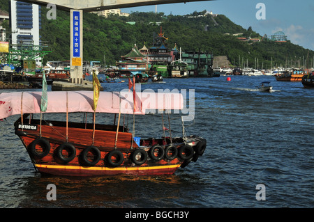 Sampan, pink canopy and flags, moored in front of the Ap Lei Chau Bridge and Jumbo Restaurant, Aberdeen Harbour, Hong Kong Stock Photo