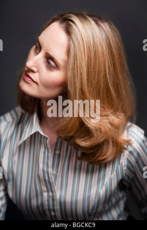 Portrait of blonde woman, looking away from camera and wearing striped shirt Stock Photo